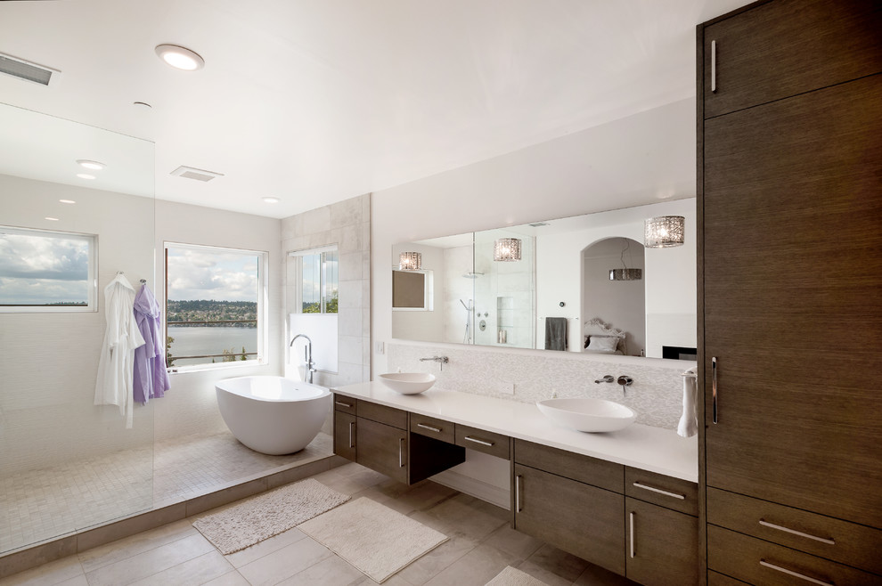 This is an example of a modern ensuite bathroom in Seattle with flat-panel cabinets, dark wood cabinets, a freestanding bath, a walk-in shower, grey tiles, ceramic tiles, white walls, porcelain flooring, a vessel sink, engineered stone worktops and an open shower.