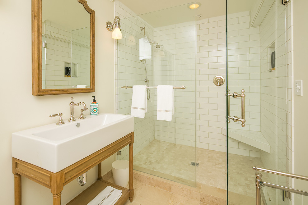 シアトルにある中くらいなトランジショナルスタイルのおしゃれなバスルーム (浴槽なし) (オープンシェルフ、淡色木目調キャビネット、アルコーブ型シャワー、白いタイル、サブウェイタイル、白い壁、トラバーチンの床、一体型シンク) の写真