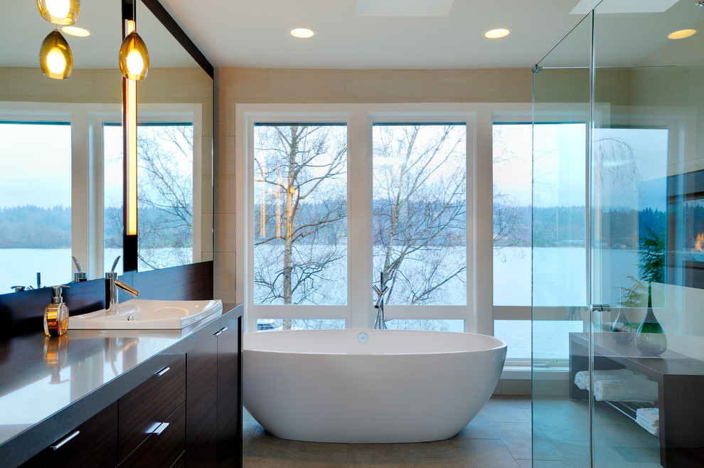 This is an example of a large contemporary ensuite bathroom in Seattle with flat-panel cabinets, dark wood cabinets, a freestanding bath, an alcove shower, beige walls and solid surface worktops.