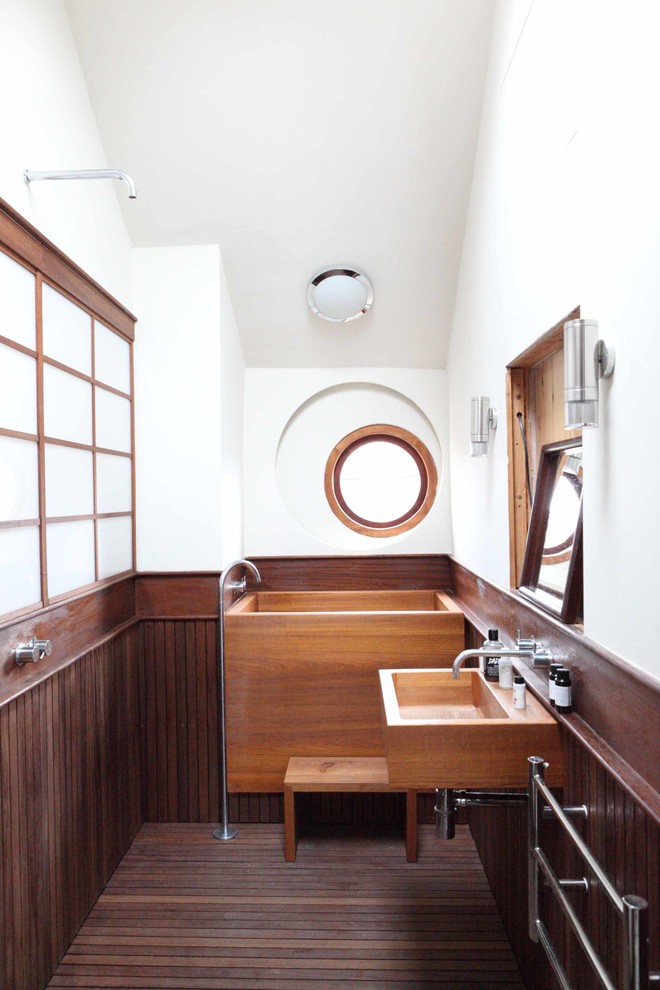 Inredning av ett asiatiskt en-suite badrum, med ett väggmonterat handfat, ett japanskt badkar, en öppen dusch, vita väggar, mörkt trägolv och med dusch som är öppen