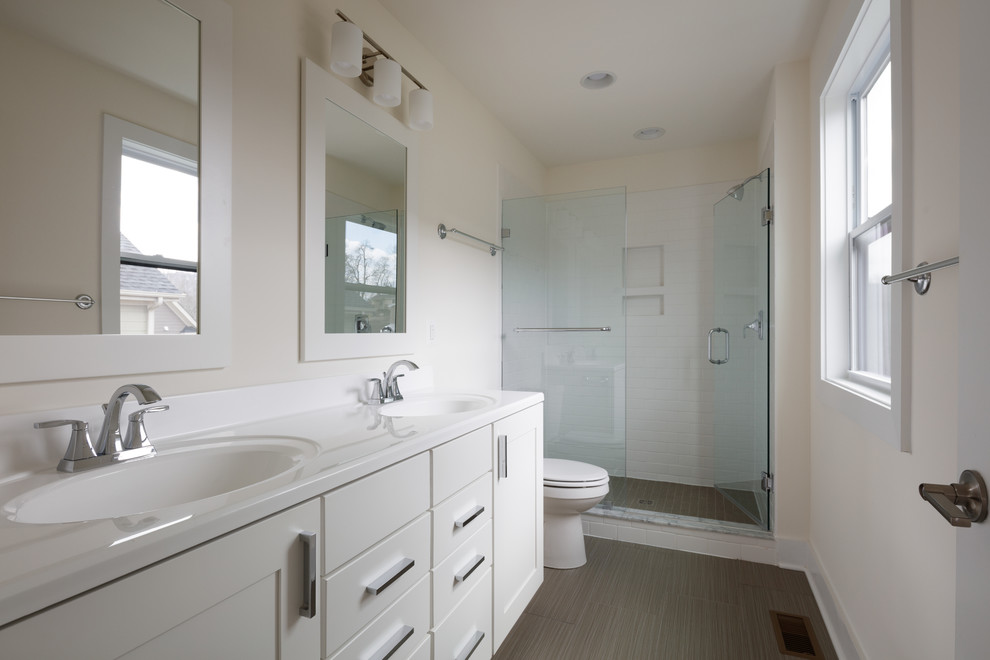 Diseño de cuarto de baño principal contemporáneo con armarios estilo shaker, puertas de armario blancas, ducha empotrada, suelo de baldosas de porcelana, lavabo integrado, encimera de acrílico, suelo gris, ducha con puerta con bisagras y encimeras blancas
