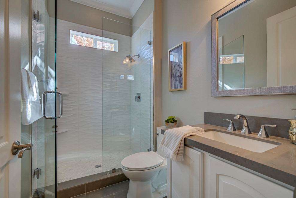 Alcove shower - transitional 3/4 gray floor alcove shower idea in Other with raised-panel cabinets, white cabinets, a two-piece toilet, beige walls, an undermount sink, a hinged shower door and gray countertops
