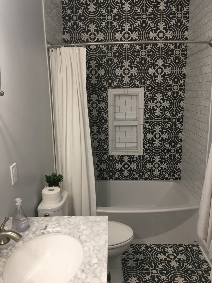 Exemple d'une salle d'eau chic de taille moyenne avec une baignoire en alcôve, un combiné douche/baignoire, un carrelage noir et blanc, des carreaux de céramique, un mur gris, un plan de toilette en marbre, une cabine de douche avec un rideau, un placard à porte affleurante, des portes de placard grises, un sol en carrelage de céramique, un lavabo encastré et un sol noir.