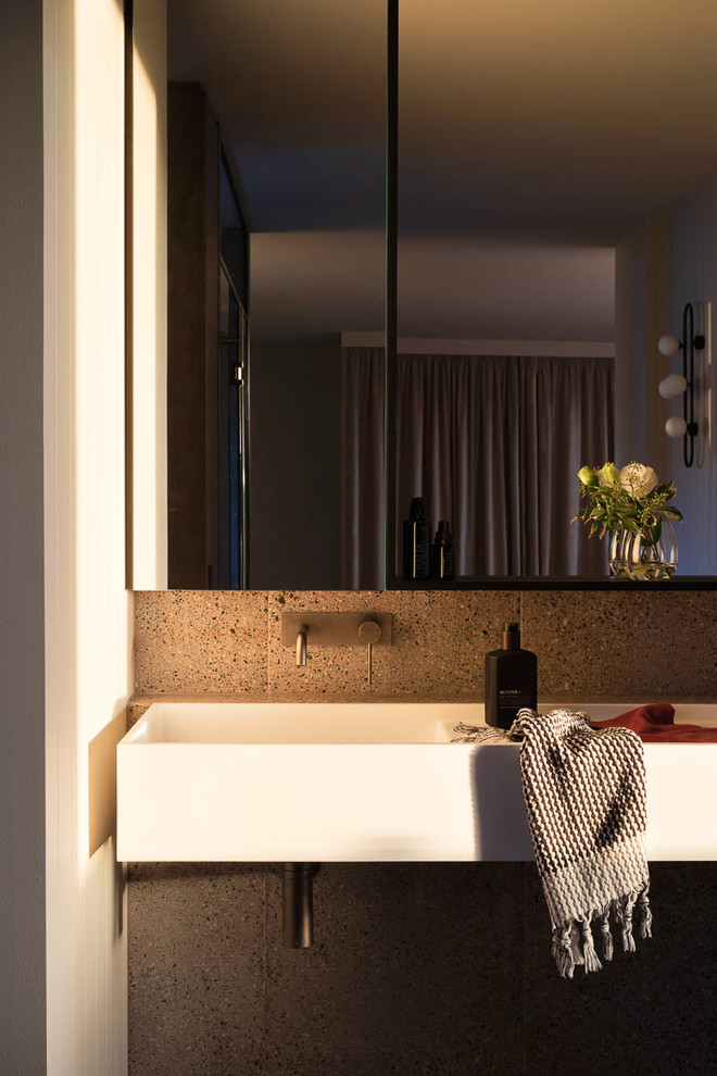 Design ideas for a large contemporary ensuite bathroom in Melbourne with flat-panel cabinets, black cabinets, a submerged bath, a double shower, a wall mounted toilet, grey tiles, ceramic tiles, grey walls, ceramic flooring, a wall-mounted sink, solid surface worktops, grey floors, a hinged door and white worktops.