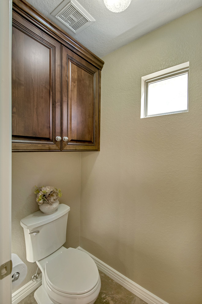 Idéer för mellanstora vintage toaletter, med luckor med upphöjd panel, skåp i mellenmörkt trä, en toalettstol med separat cisternkåpa, beige kakel, porslinskakel, beige väggar, klinkergolv i porslin, ett undermonterad handfat och granitbänkskiva