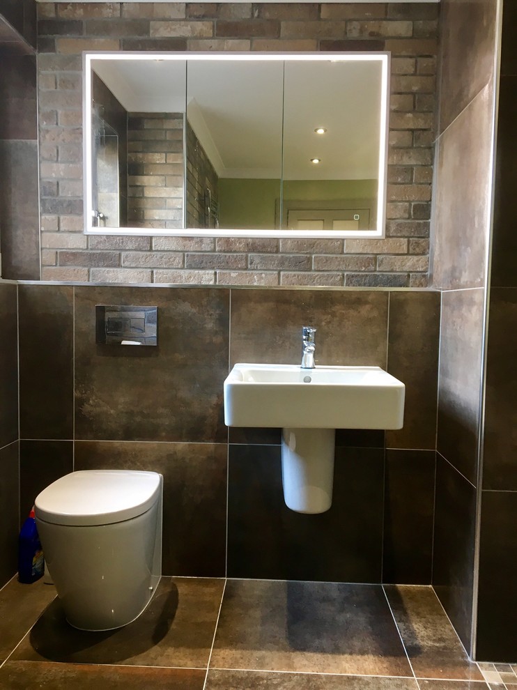 Bild på ett mellanstort rustikt badrum för barn, med ett platsbyggt badkar, en öppen dusch, en toalettstol med hel cisternkåpa, brun kakel, klinkergolv i porslin, ett piedestal handfat, kaklad bänkskiva och brunt golv