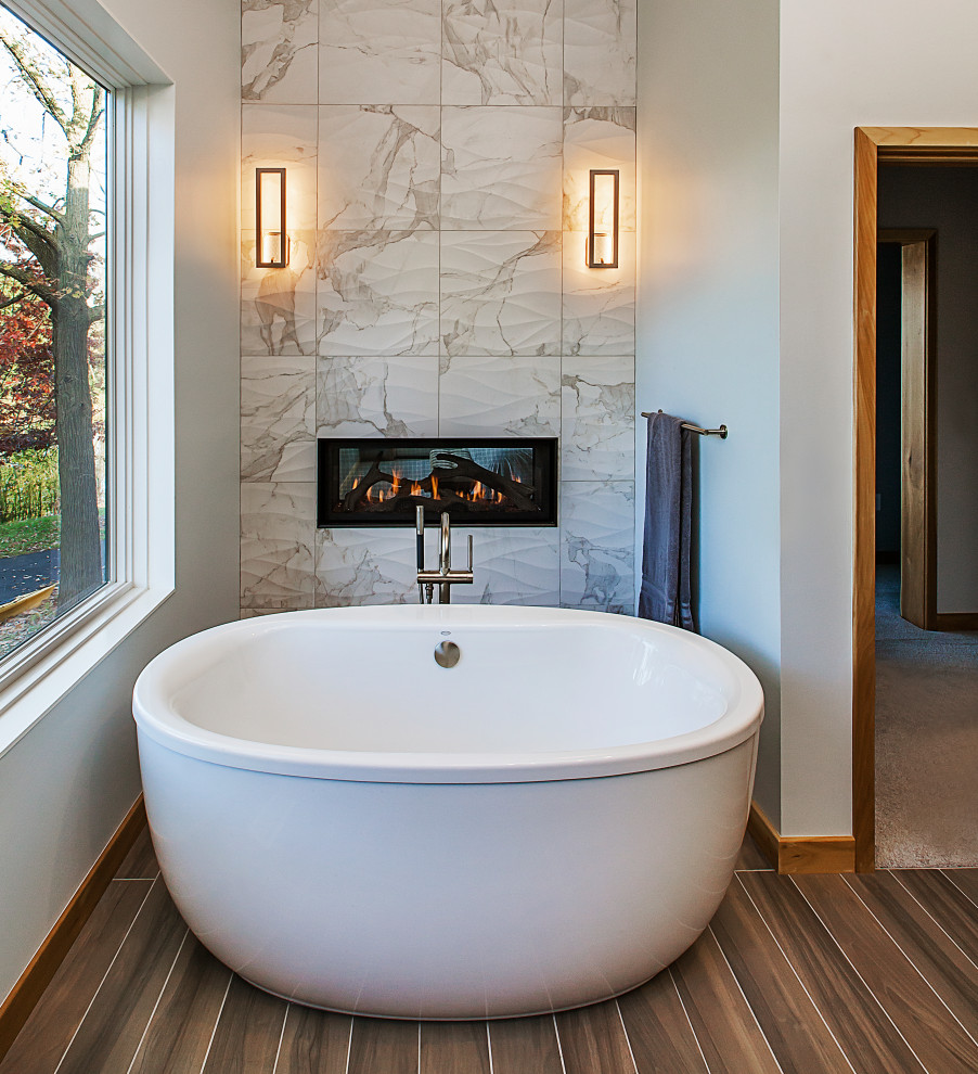 Ejemplo de cuarto de baño principal contemporáneo de tamaño medio con bañera exenta, baldosas y/o azulejos beige, baldosas y/o azulejos de porcelana, paredes grises y suelo marrón
