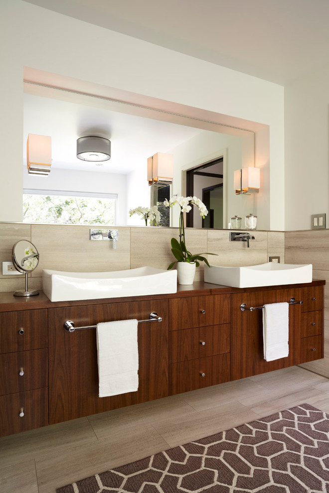 Trendy beige tile bathroom photo in Minneapolis with a vessel sink, flat-panel cabinets, dark wood cabinets, wood countertops and brown countertops