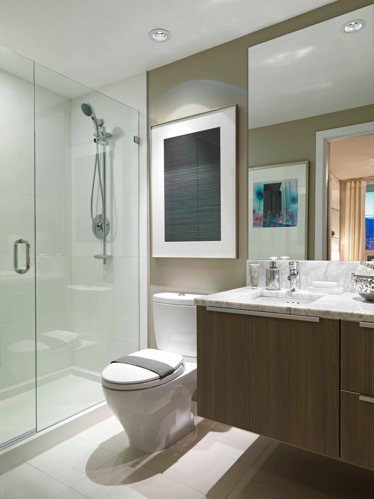 На фото: ванная комната в современном стиле с врезной раковиной, плоскими фасадами, темными деревянными фасадами, мраморной столешницей, раздельным унитазом, белой плиткой и керамогранитной плиткой