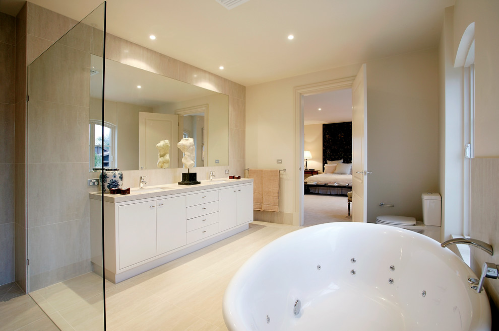 На фото: главная ванная комната в современном стиле с плоскими фасадами, гидромассажной ванной, душем без бортиков, раздельным унитазом и бежевыми стенами