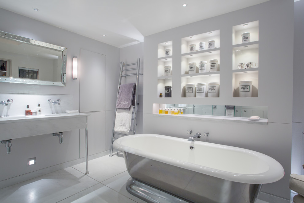 Cette image montre une salle de bain design avec une baignoire indépendante et un mur blanc.