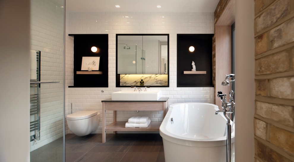 Imagen de cuarto de baño principal actual de tamaño medio con baldosas y/o azulejos blancos, baldosas y/o azulejos de porcelana, lavabo tipo consola, bañera exenta, ducha esquinera, sanitario de pared y paredes blancas