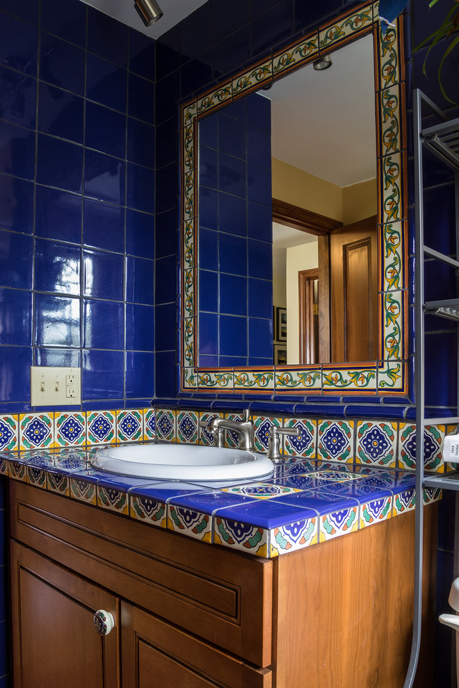 Immagine di una stanza da bagno con doccia american style di medie dimensioni con ante in stile shaker, ante in legno scuro, piastrelle blu, piastrelle in ceramica, lavabo da incasso e top piastrellato