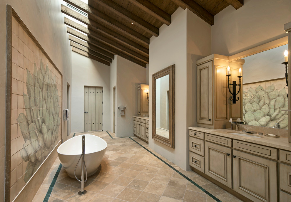 Idee per una stanza da bagno padronale mediterranea con ante con bugna sagomata, ante in legno chiaro, vasca freestanding, pareti beige, pavimento in gres porcellanato e lavabo sottopiano