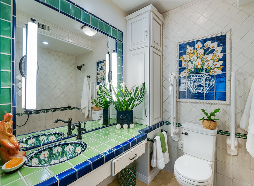 Photo of a small mediterranean ensuite bathroom in San Diego with raised-panel cabinets, white cabinets, a two-piece toilet, green tiles, terracotta tiles, white walls, porcelain flooring, a submerged sink and tiled worktops.