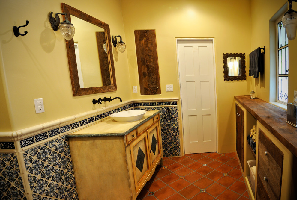 На фото: ванная комната среднего размера в стиле фьюжн с желтыми стенами, полом из терракотовой плитки, настольной раковиной, красным полом, фасадами с утопленной филенкой, искусственно-состаренными фасадами, душем в нише, душевой кабиной, столешницей из дерева и душем с распашными дверями с