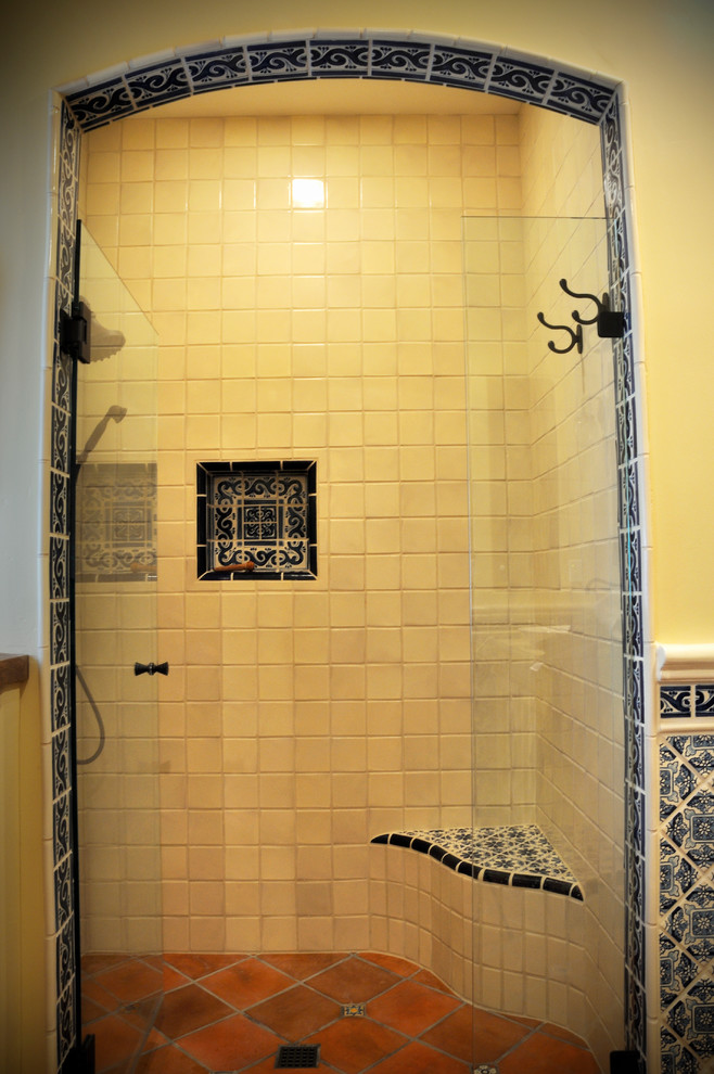 Inredning av ett amerikanskt mellanstort badrum med dusch, med luckor med infälld panel, skåp i slitet trä, en dusch i en alkov, gula väggar, klinkergolv i terrakotta, ett fristående handfat, träbänkskiva, rött golv och dusch med gångjärnsdörr