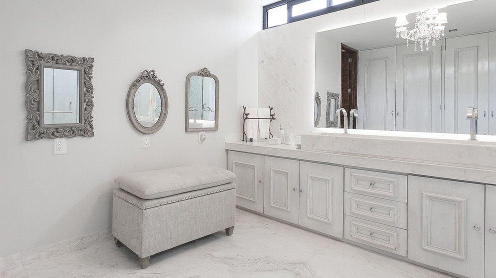 Bathroom - transitional white tile marble floor bathroom idea in Mexico City with a trough sink, recessed-panel cabinets, white cabinets and white walls