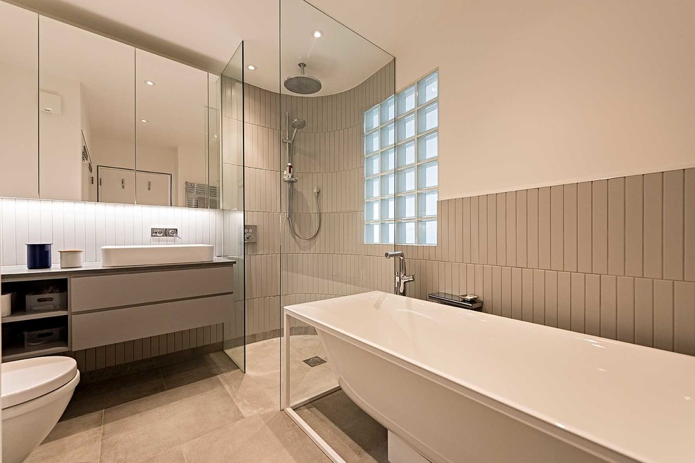 Design ideas for a medium sized contemporary ensuite bathroom in London with flat-panel cabinets, grey cabinets, white walls, a vessel sink, grey floors, an open shower, grey worktops, a freestanding bath, a corner shower and grey tiles.