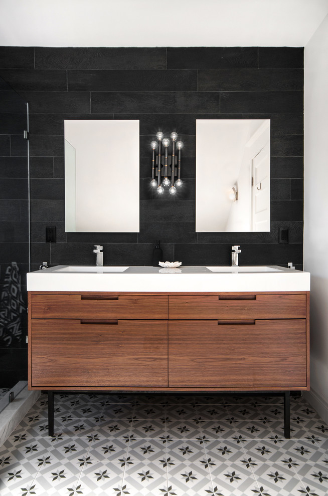 Cette image montre une salle de bain design en bois brun avec un lavabo intégré, un placard à porte plane, un carrelage noir, un carrelage noir et blanc et un mur noir.