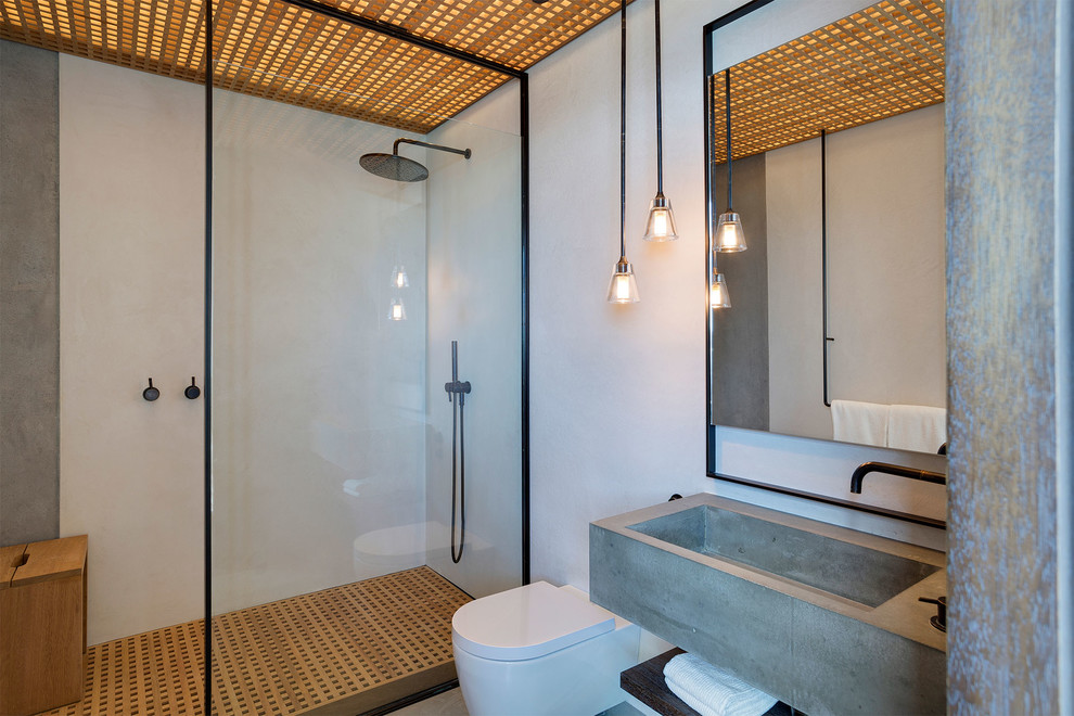 Immagine di una stanza da bagno padronale design di medie dimensioni con nessun'anta, WC sospeso, doccia aperta, doccia aperta, pareti bianche, lavabo sospeso, top in cemento e top grigio