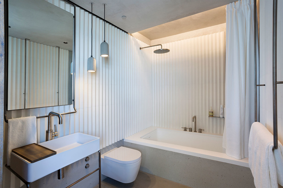 Exempel på ett mellanstort modernt brun brunt en-suite badrum, med en dusch/badkar-kombination, dusch med duschdraperi, en vägghängd toalettstol, ett undermonterat badkar, vita väggar, ett fristående handfat och grått golv