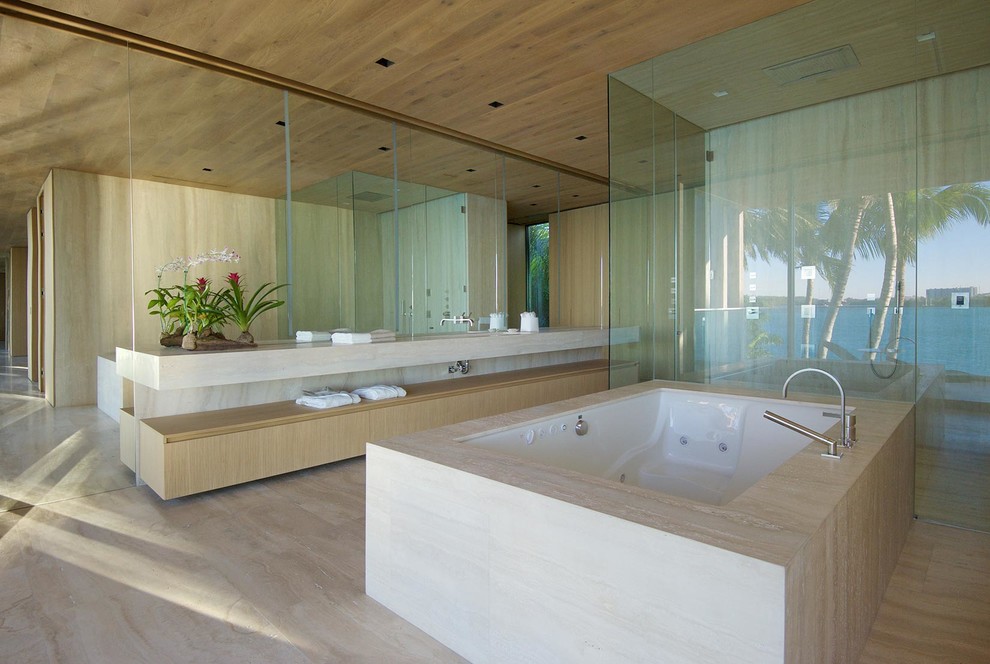 Inspiration for a contemporary bathroom in Miami with flat-panel cabinets, light wood cabinets, a submerged bath, a built-in shower, beige tiles, beige walls, beige floors, a hinged door and beige worktops.