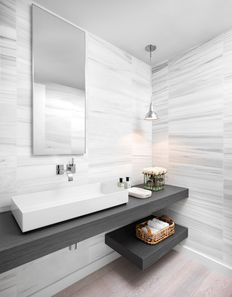 Medium sized contemporary ensuite bathroom in Miami with open cabinets, grey tiles, white tiles, light hardwood flooring, a vessel sink, grey cabinets, stone tiles, grey walls, wooden worktops and brown floors.