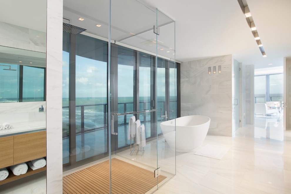 マイアミにあるラグジュアリーな広いコンテンポラリースタイルのおしゃれなマスターバスルーム (フラットパネル扉のキャビネット、中間色木目調キャビネット、置き型浴槽、コーナー設置型シャワー、大理石の床、開き戸のシャワー) の写真
