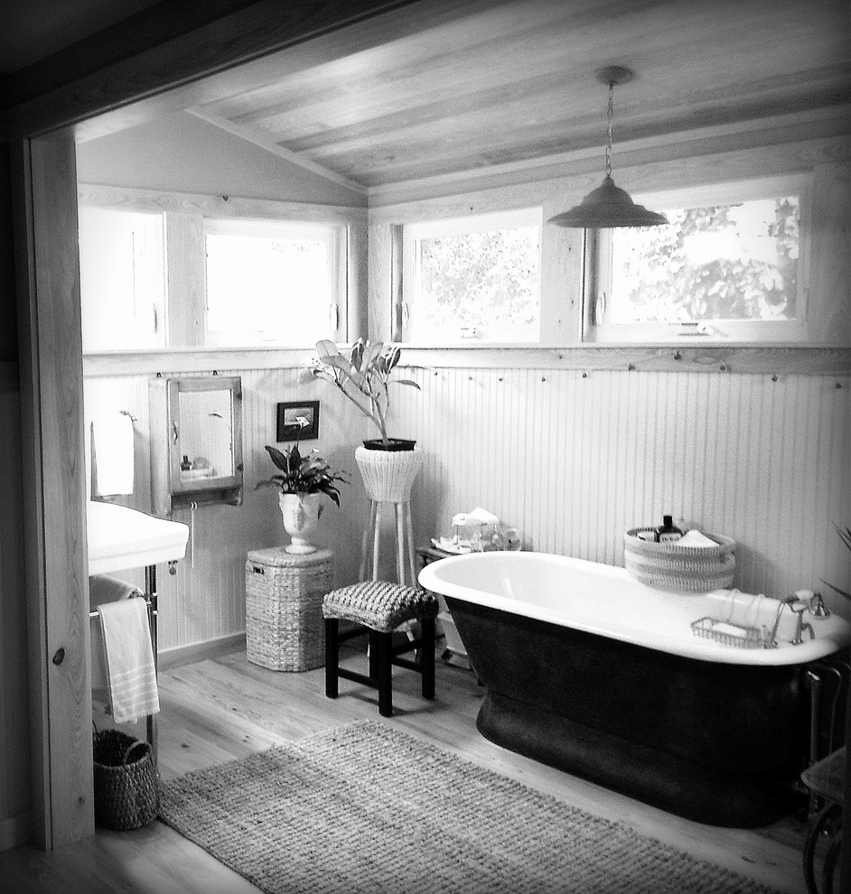 Diseño de cuarto de baño principal de estilo de casa de campo de tamaño medio con bañera con patas y suelo de madera clara