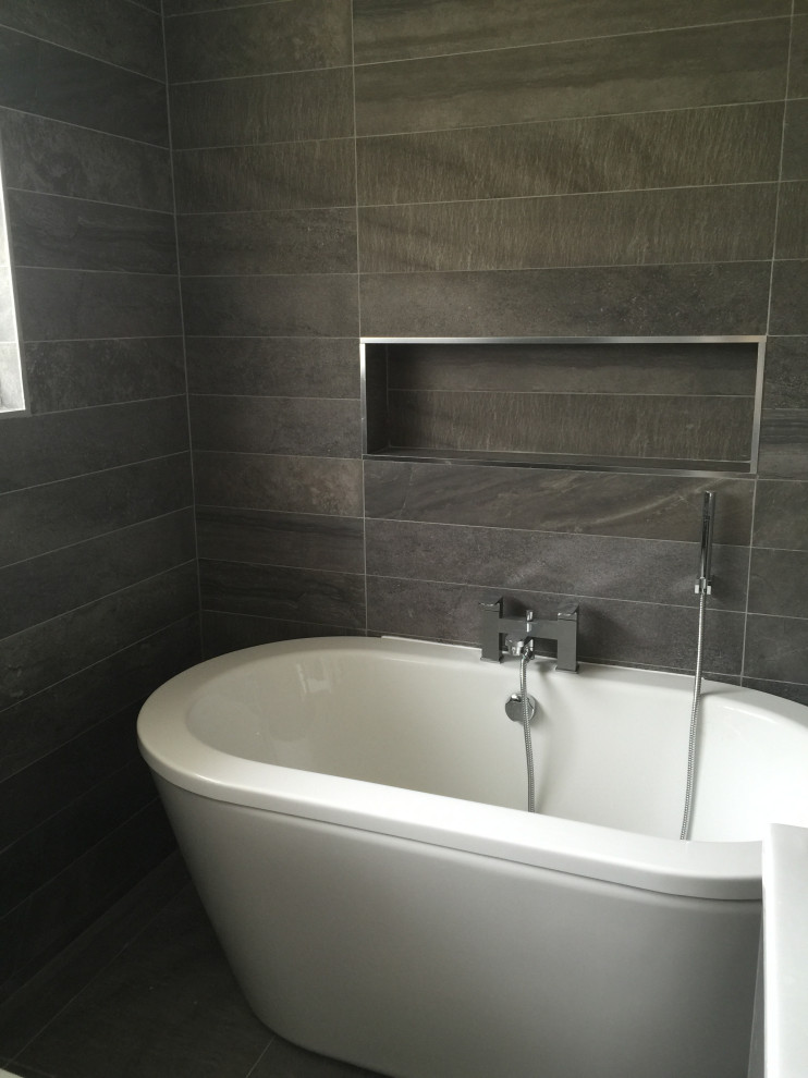 Design ideas for a medium sized contemporary family bathroom in London with flat-panel cabinets, grey cabinets, a freestanding bath, a corner shower, a wall mounted toilet, grey tiles, ceramic tiles, grey walls, ceramic flooring, a wall-mounted sink, grey floors and a hinged door.