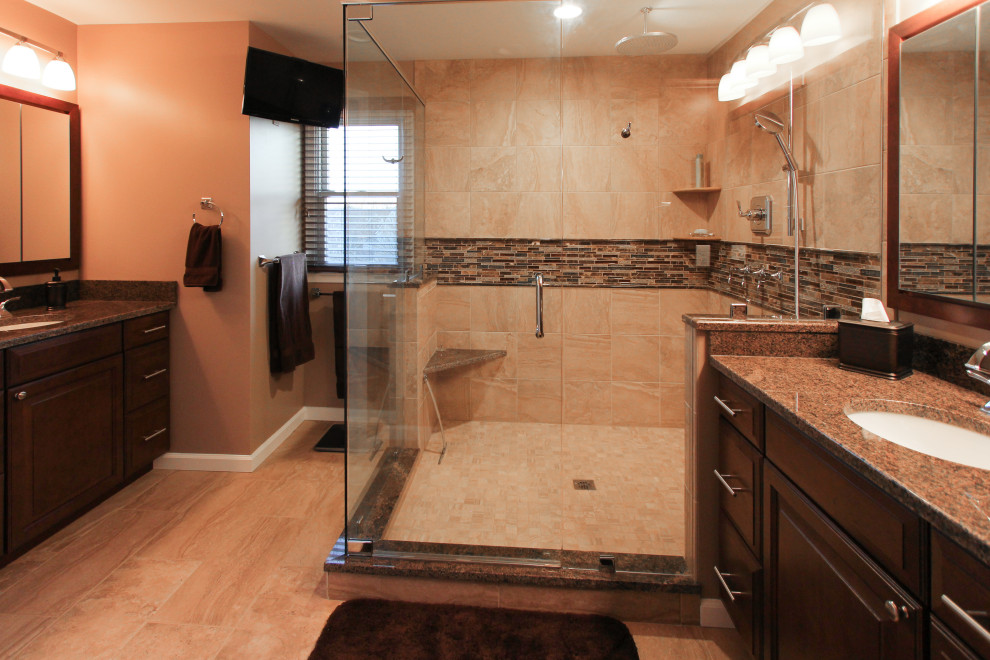 Inspiration for a large transitional master beige tile and porcelain tile porcelain tile and beige floor corner shower remodel in Philadelphia with shaker cabinets, dark wood cabinets, a two-piece toilet, beige walls, an undermount sink, granite countertops, a hinged shower door and brown countertops