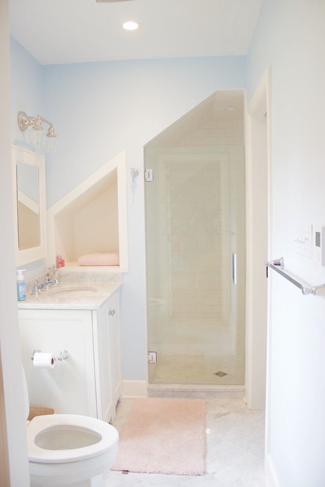 Foto på ett mellanstort amerikanskt badrum med dusch, med luckor med profilerade fronter, vita skåp, en dusch i en alkov, en toalettstol med hel cisternkåpa, vit kakel, tunnelbanekakel, blå väggar, marmorgolv, ett undermonterad handfat och marmorbänkskiva