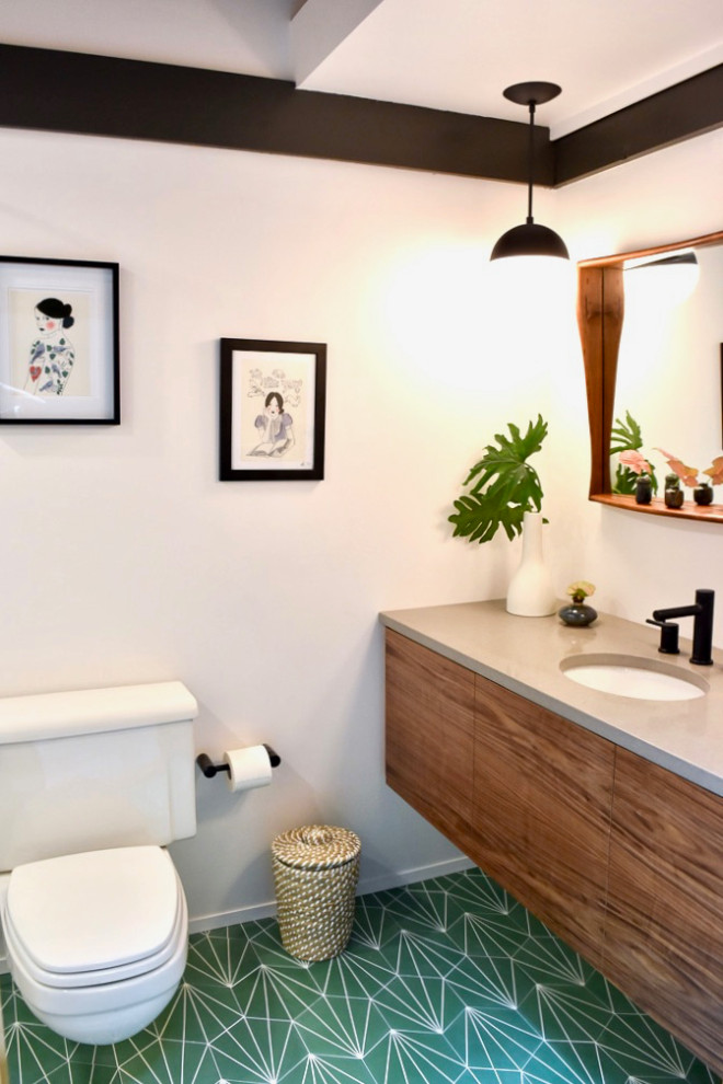 Foto på ett litet 60 tals grå badrum med dusch, med släta luckor, skåp i mörkt trä, en vägghängd toalettstol, vit kakel, keramikplattor, vita väggar, cementgolv, ett undermonterad handfat, bänkskiva i kvarts och grönt golv