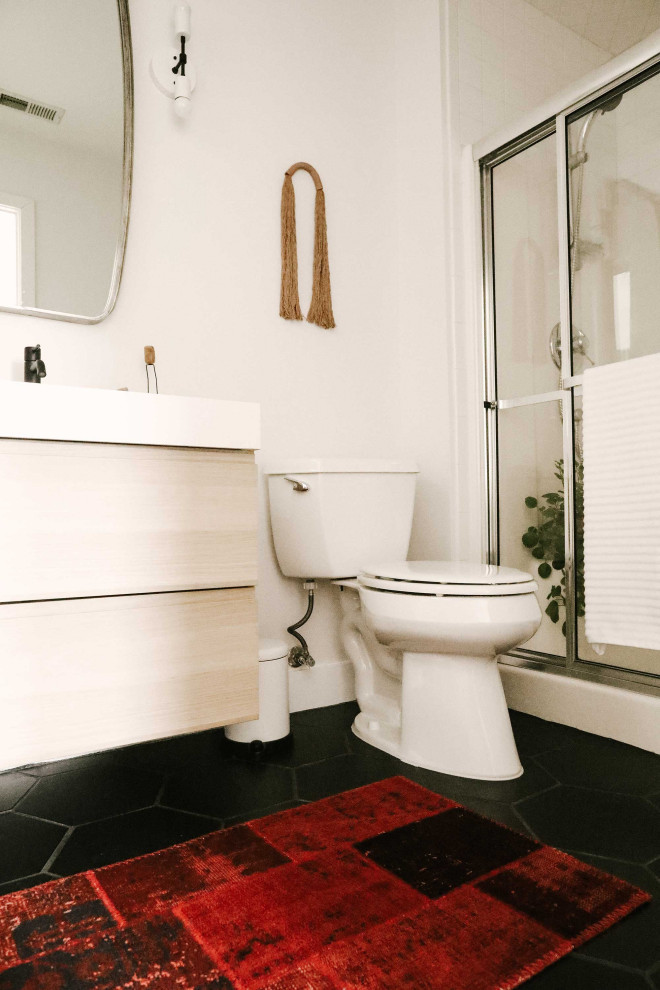 Small retro family bathroom in Other with flat-panel cabinets, light wood cabinets, a two-piece toilet, white walls, an integrated sink, black floors, a sliding door, white worktops, a single sink and a floating vanity unit.