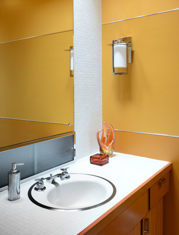 Стильный дизайн: ванная комната среднего размера в современном стиле с плоскими фасадами, фасадами цвета дерева среднего тона, душем в нише, желтыми стенами, полом из ламината, монолитной раковиной и столешницей из плитки - последний тренд