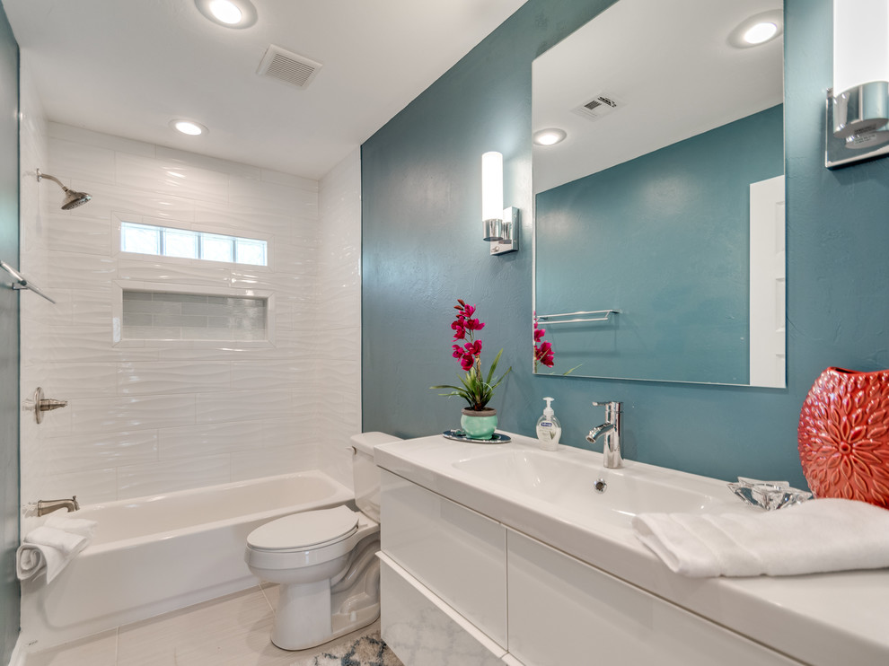 На фото: ванная комната в стиле ретро с белыми фасадами, ванной в нише, душем над ванной, белой плиткой, синими стенами, полом из керамической плитки и серым полом с