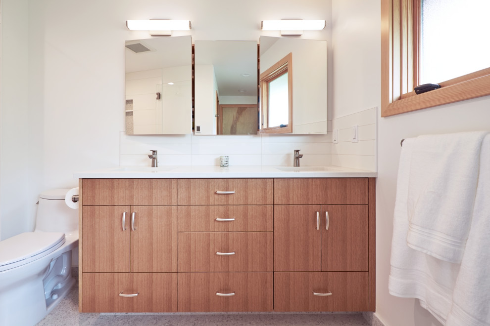 Photo of a medium sized retro ensuite bathroom in Seattle with flat-panel cabinets, light wood cabinets, a built-in shower, a two-piece toilet, white tiles, ceramic tiles, white walls, porcelain flooring, a submerged sink, engineered stone worktops, grey floors, a hinged door, white worktops, a wall niche, a single sink and a built in vanity unit.