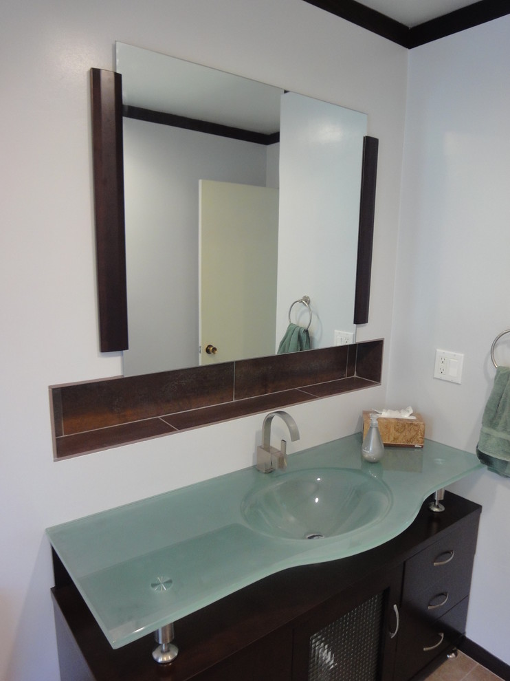 This is an example of a medium sized retro ensuite bathroom in Los Angeles with flat-panel cabinets, dark wood cabinets, a one-piece toilet, multi-coloured tiles, ceramic tiles, white walls, ceramic flooring, an integrated sink and glass worktops.