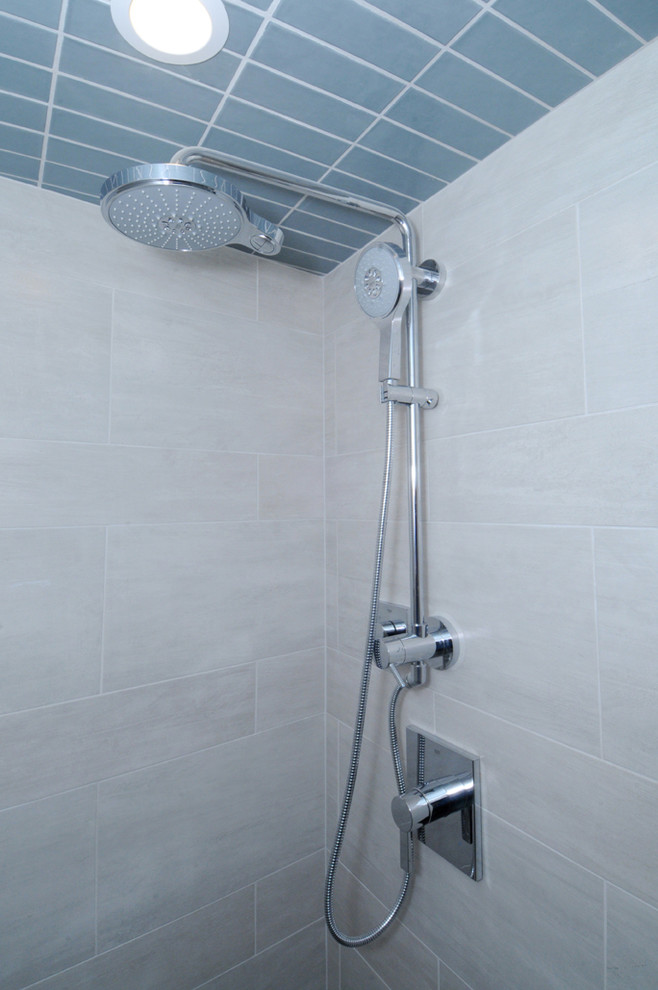 Foto på ett stort retro badrum, med släta luckor, vita skåp, ett fristående badkar, en öppen dusch, en toalettstol med hel cisternkåpa, porslinskakel, grå väggar, ett undermonterad handfat och laminatbänkskiva