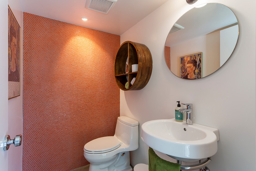 Idéer för retro badrum, med öppna hyllor, vita skåp, en toalettstol med hel cisternkåpa, orange kakel, orange väggar, betonggolv, ett väggmonterat handfat och grått golv