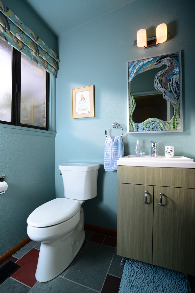 Inspiration för ett 50 tals badrum, med släta luckor, skåp i ljust trä, en toalettstol med separat cisternkåpa, blå väggar, klinkergolv i porslin, ett integrerad handfat och flerfärgat golv
