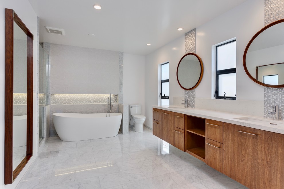 Example of a large 1950s master glass sheet marble floor and white floor bathroom design in Los Angeles with open cabinets, medium tone wood cabinets, a two-piece toilet, white walls, an undermount sink, quartz countertops and a hinged shower door