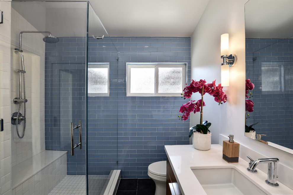 Modelo de cuarto de baño retro con baldosas y/o azulejos azules, paredes blancas y ducha con puerta con bisagras