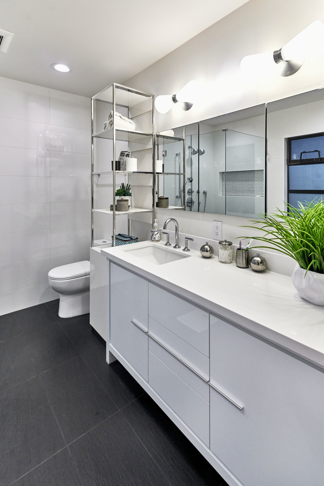 Large midcentury ensuite bathroom in San Francisco with flat-panel cabinets, white cabinets, a one-piece toilet, white tiles, white walls, a submerged sink, quartz worktops and black floors.