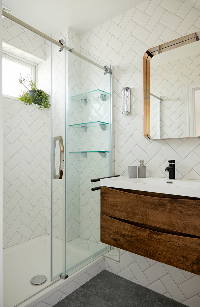 Foto på ett litet 50 tals badrum, med släta luckor, bruna skåp, en kantlös dusch, tunnelbanekakel, ett väggmonterat handfat, grått golv och dusch med skjutdörr