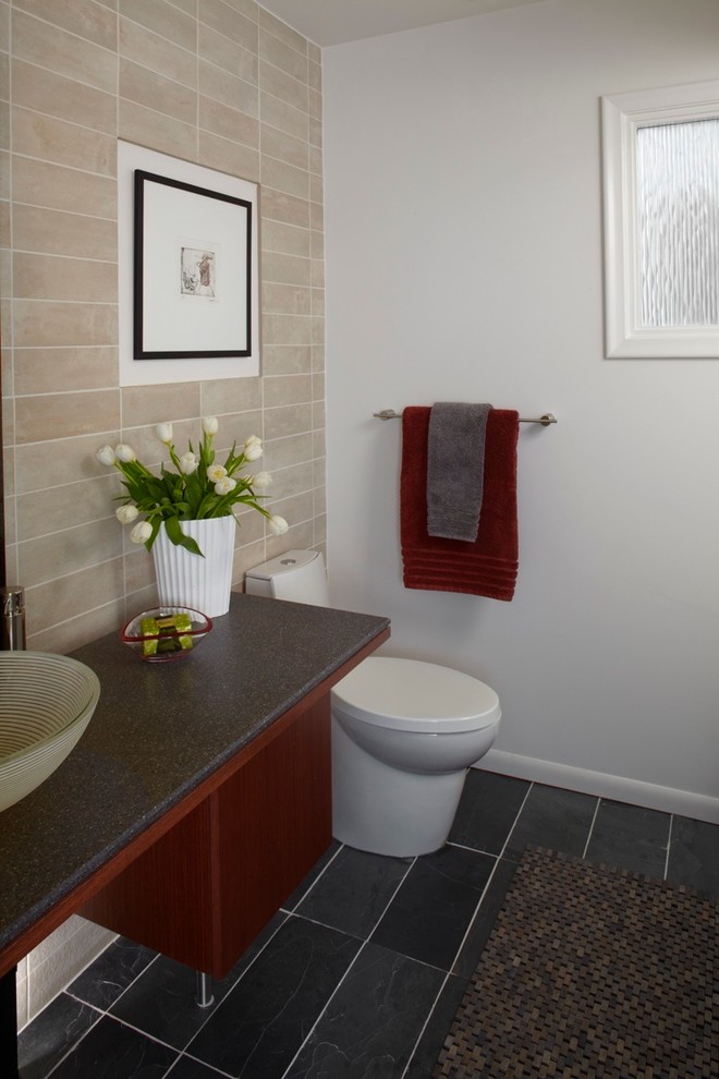 Cette photo montre une petite salle de bain moderne en bois brun avec un placard à porte plane, une baignoire encastrée, un combiné douche/baignoire, WC à poser, un carrelage beige, des carreaux de porcelaine, un mur blanc, un sol en ardoise, un plan de toilette en surface solide et une vasque.