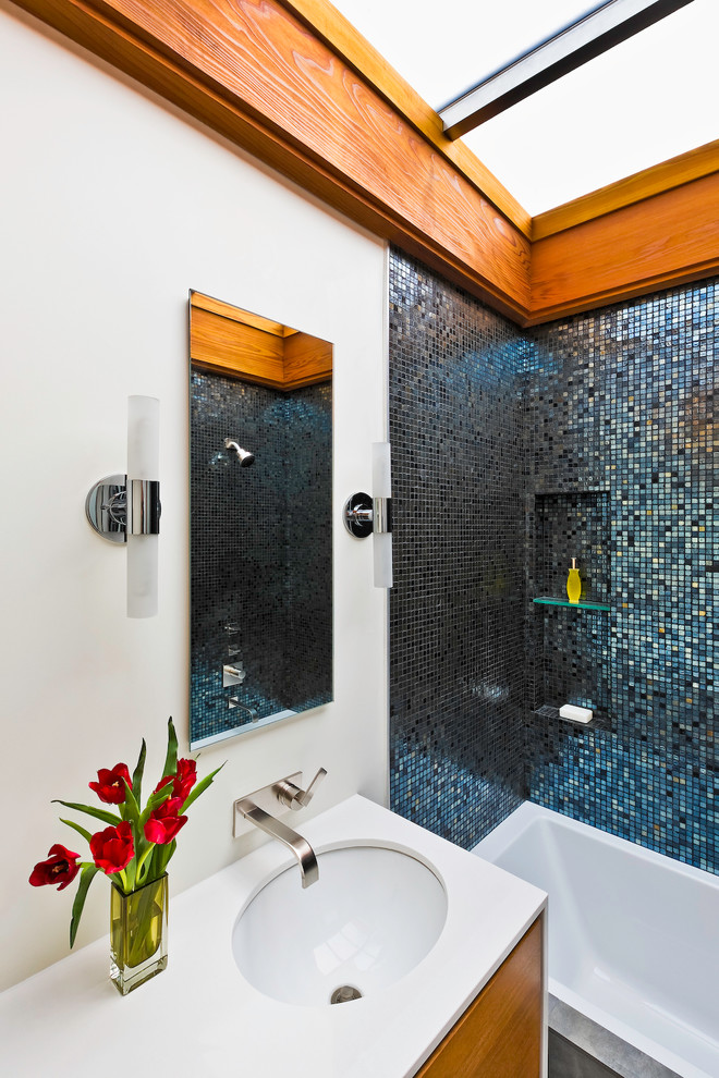 На фото: ванная комната среднего размера в стиле ретро с плоскими фасадами, фасадами цвета дерева среднего тона, ванной в нише, душем в нише, синей плиткой, плиткой из листового стекла, белыми стенами, душевой кабиной, врезной раковиной, шторкой для ванной и белой столешницей с