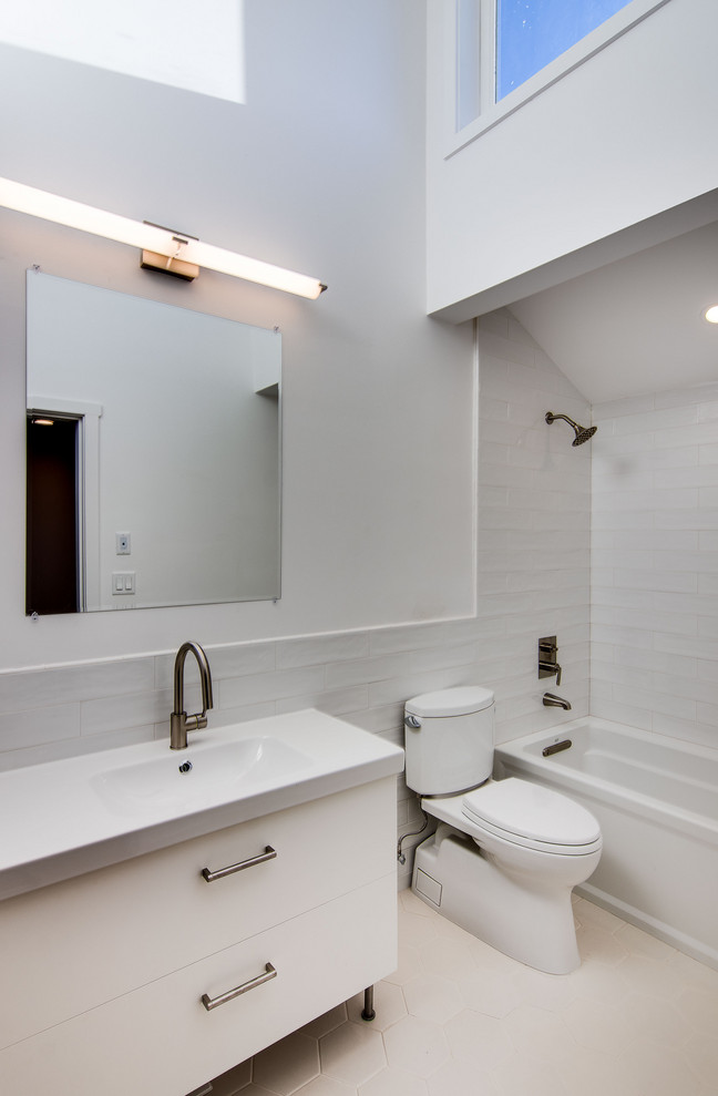 Пример оригинального дизайна: огромная детская, серо-белая ванная комната в стиле ретро с плоскими фасадами, белыми фасадами, ванной в нише, душем над ванной, раздельным унитазом, белой плиткой, керамогранитной плиткой, белыми стенами, светлым паркетным полом, монолитной раковиной, стеклянной столешницей, коричневым полом, шторкой для ванной и белой столешницей