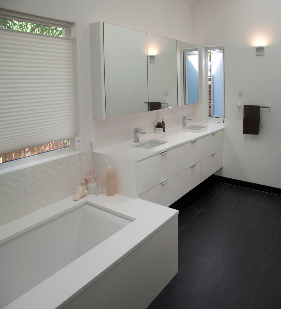 Источник вдохновения для домашнего уюта: главная ванная комната среднего размера в стиле ретро с плоскими фасадами, белыми фасадами, полновстраиваемой ванной, инсталляцией, белой плиткой, белыми стенами, полом из керамогранита, подвесной раковиной, столешницей из искусственного кварца, душевой комнатой, керамогранитной плиткой, серым полом, душем с распашными дверями и белой столешницей